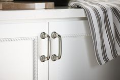 a close up of two handles on a white cabinet with a towel hanging from it