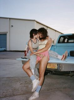 two women hugging each other in front of a truck