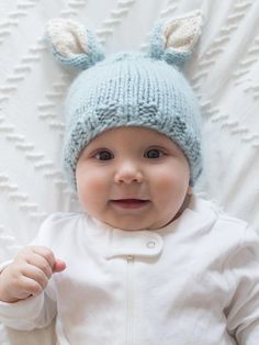 a baby wearing a blue knitted hat with ears