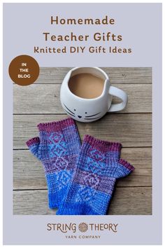 two knitted mitts sitting on top of a wooden table next to a cup of coffee