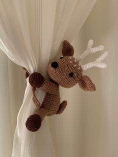 a crocheted stuffed animal hanging from the side of a curtain with white drapes