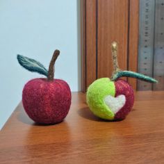 two felt apples sitting on top of a wooden table