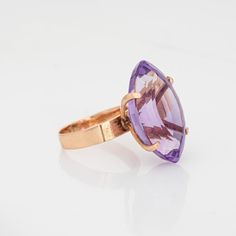 Stylish vintage amethyst ring crafted in 18 karat rose gold (circa 1960s).   Marquise cut amethyst measures 24mm x 15mm (estimated at 17.50 carats). The amethyst is in very good condition and free of cracks or chips.   The distinct cocktail ring highlights a beautiful marquise cut amethyst, perched high in a four pronged mount. The high rise mount allows for all of the beauty of the amethyst to be on full display, with the facets visible underneath the mounting. Bold in color and style the ring makes a great statement on the hand. The high rise ring (15mm - 0.59 inches) sits comfortably on the finger.    The ring is in good condition and was lightly cleaned and polished.   Particulars:  Weight: 7.3 grams  Stones:  Marquise cut amethyst measures 24mm x 15mm (estimated at 17.50 carats). The Classic Marquise Amethyst Ring, Luxury Gold Marquise Amethyst Ring, Luxury Marquise Amethyst Ring, Marquise Amethyst Ring In 14k Gold, Luxury Marquise-cut Amethyst Ring, Amethyst Ring Vintage, Sapphire Cocktail Ring, Cocktail Jewelry, Gold Cocktail