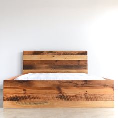 a bed made out of wooden planks in a room with white walls and flooring