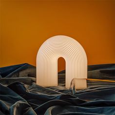 a white sculpture sitting on top of a bed next to an orange wall in the background