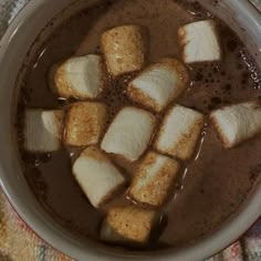 a bowl filled with brown liquid and marshmallows