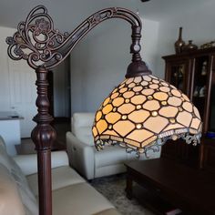 a lamp that is sitting on top of a stand in a living room next to a couch