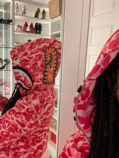 a woman wearing a red and pink hoodie in front of a mirror