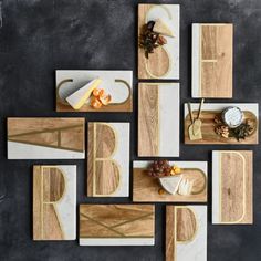 several wooden cutting boards with cheese and fruit on them, arranged in the shape of letters