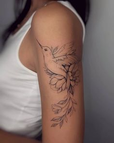 a woman's arm with a bird and flower tattoo on the left side of her arm