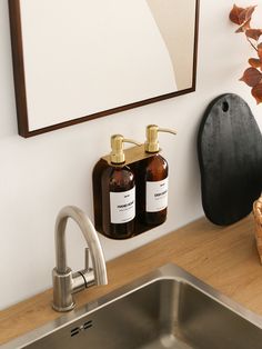 two soap dispensers are hanging on the wall next to a kitchen sink