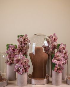 there are vases with flowers in them on the table next to each other and a mannequin