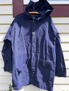 1980's dark indigo cotton canvas hooded parka. Brand is Peace Blues. Made in the USA. Buttons down front. Beautiful patina and definitely wearable  but does have some condition issues: missing drawstring for waist, missing second from bottom button, front pocket is ripped at the seam and some light discoloration on front and back. Please refer to pictures. Sold as is. Tagged Small but definitely not accurate. Was meant to be quite oversized. Measured flat:  Shoulder: 24" Chest: 24" Length: 35" Sleeve: 25" Best fit: Unisex Large to XL. Please measure against yourself for best fit. Cotton Dark Wash Outerwear For Outdoor, Dark Wash Cotton Outerwear For Outdoor, Oversized Cotton Parka With Double-lined Hood, Casual Navy Hooded Parka, Utility Cotton Hooded Jacket With Double-lined Hood, Oversized Cotton Parka With Drawstring Hood, Vintage Cotton Parka For Fall, Casual Cotton Parka With Drawstring Hood, Blue Cotton Hooded Jacket With Pockets