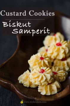 some cookies are on a wooden plate with the words, custard cookies biscuit samperit