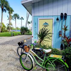 two bikes parked next to each other in front of a blue and yellow building with palm trees