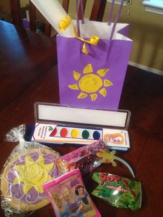 a purple bag sitting on top of a wooden table next to some candy and other items