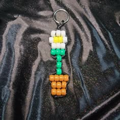 a keychain made out of legos on a black cloth with some colored beads