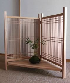 a small potted plant sitting inside of a wooden screen