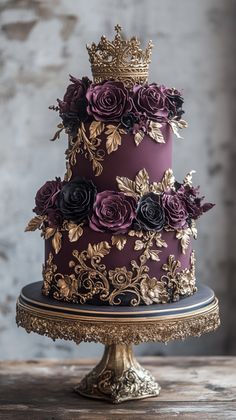 a three tiered cake with purple and gold flowers on top is sitting on a table