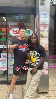 two young men standing next to each other in front of a store