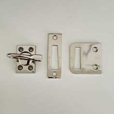 two metal latches are next to each other on a white surface with holes in the middle