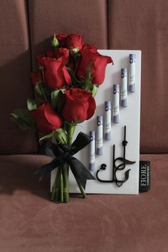 a bouquet of red roses sitting on top of a white board with writing and pens