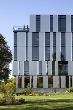 two people are standing on the roof of a building with many windows and balconies