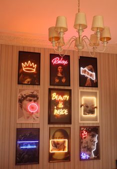 a chandelier hanging from the ceiling in front of a wall with neon signs