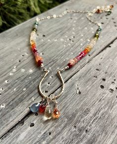 If you're looking for a handmade gift, this beautiful, delicate artisan necklace contains a full rainbow of gemstones! Ruby, sunstone, citrine, tourmaline, topaz, fire opal, apatite, sapphire and more form a gemstone rainbow strand. In the center, a sterling silver horseshoe holds sparkling briolettes of sapphire, citrine and zircon.  Necklace measures 15.5 to 17.5 inches with a 2 inch extender chain. Horseshoe is about 1 inch long, total drop length (horseshoe and briolettes) is about 1.5 inches.  This piece is one of a kind, and you will receive the exact necklace pictured. Necklace care: To protect the delicate gemstones, please handle with care. Remove before showering or bathing, exercising, or applying lotion, perfume, or sunscreen. Silk may stretch when wet, so please keep dry, and Fine Jewelry Handmade Teardrop Necklace, Sterling Silver Teardrop Necklace With Gemstone Accents, Dainty Sterling Silver Necklace With Gemstone Accents, Artisan Drop Gemstone Necklace, Dangle Sterling Silver Necklaces With Gemstone Accents, Sterling Silver Necklaces With Gemstone Accents In Dangle Shape, Dazzling Sterling Silver Necklaces With Gemstone Accents, Sterling Silver Necklace With Briolette Gemstone Accents, Sterling Silver Birthstone Necklace With Briolette Gemstone