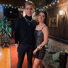 a young man and woman standing next to each other in a room with wood floors