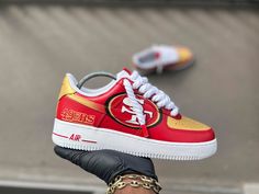 a person holding up a red and yellow nike air force 1 shoe in their hand