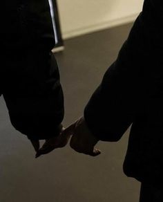 two people holding hands while standing next to each other in front of a door way