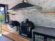 an outdoor kitchen with large black grills on the counter top and oven hood over it