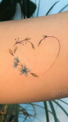 a heart shaped tattoo with flowers on the side of the arm and an arrow in the middle