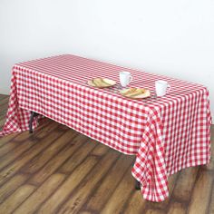 a red and white checkered table cloth with two plates on it sitting on a wooden floor