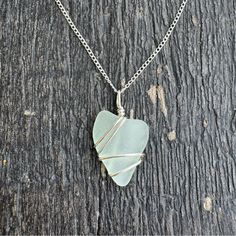 a necklace with a heart shaped glass piece hanging from it's side on a wooden surface