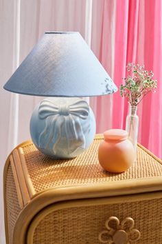 a blue lamp sitting on top of a wicker table next to a vase with flowers