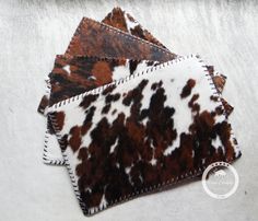 three pieces of cow print fabric sitting on top of a white sheet covered in brown and black spots