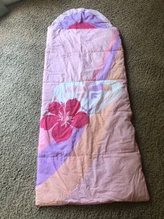 a pink and purple sleeping bag laying on the floor