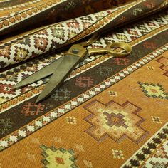 a pair of scissors sitting on top of a colorful rug with intricate designs and colors