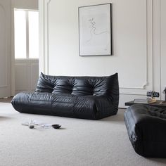 a living room with two black leather couches and a white rug on the floor