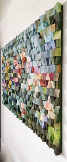 a large wall sculpture made out of many different colored pieces of paper on a white wall