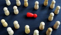 a group of wooden pegs with one red piece in the middle surrounded by white ones