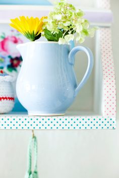 a blue vase filled with flowers on top of a shelf