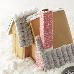 a house made out of cardboard sitting on top of white fluffy carpet next to cookies