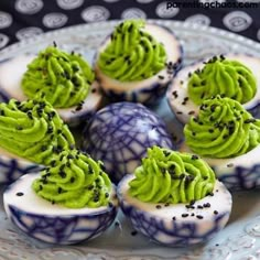 green frosted cupcakes with sprinkles on them are sitting on a blue and white plate