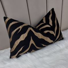 a black and gold zebra print pillow sitting on top of a white fur covered bed