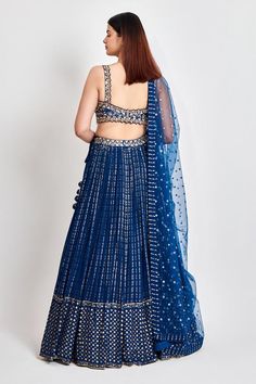 Blue lehenga with all over zari work in striped pattern. Paired with a cutwork embroidered padded blouse in zari, dabka and nakshi and an embroidered dupatta.
Components: 3
Pattern: Embroidered
Type Of Work: Zari, Dabka, Nakshi
Neckline: Sweetheart
Sleeve Type: Sleeveless
Fabric: Georgette
Color: Blue
Other Details: 
Embroidered dupatta
Length
Blouse: 14.5 inches
Lehenga: 45 inches
Approx. product weight: 4 kgs
Closure:
Lehenga: Zipper
Model Height: 5 ft 9 inches, wearing size M
Occasion: Weddin Elegant Blue Choli With Dori Work, Designer Blue Choli With Dori Work, Blue Fitted Lehenga With Mirror Work, Fitted Blue Lehenga With Mirror Work, Blue Choli With Dori Work For Party, Blue Cutdana Choli For Navratri, Fitted Blue Choli With Mirror Work, Diwali Blue Choli With Cutdana Details, Blue Cutdana Choli For Diwali