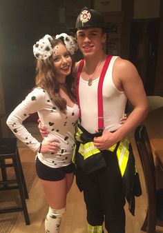 a man and woman dressed in costumes posing for a photo together with fireman's gear