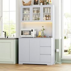 a kitchen area with a microwave, counter and cabinets in white painted wood flooring